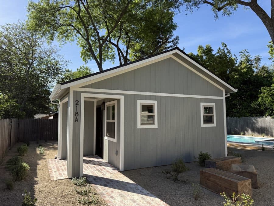 Detached backyard ADU with light siding and covered entry